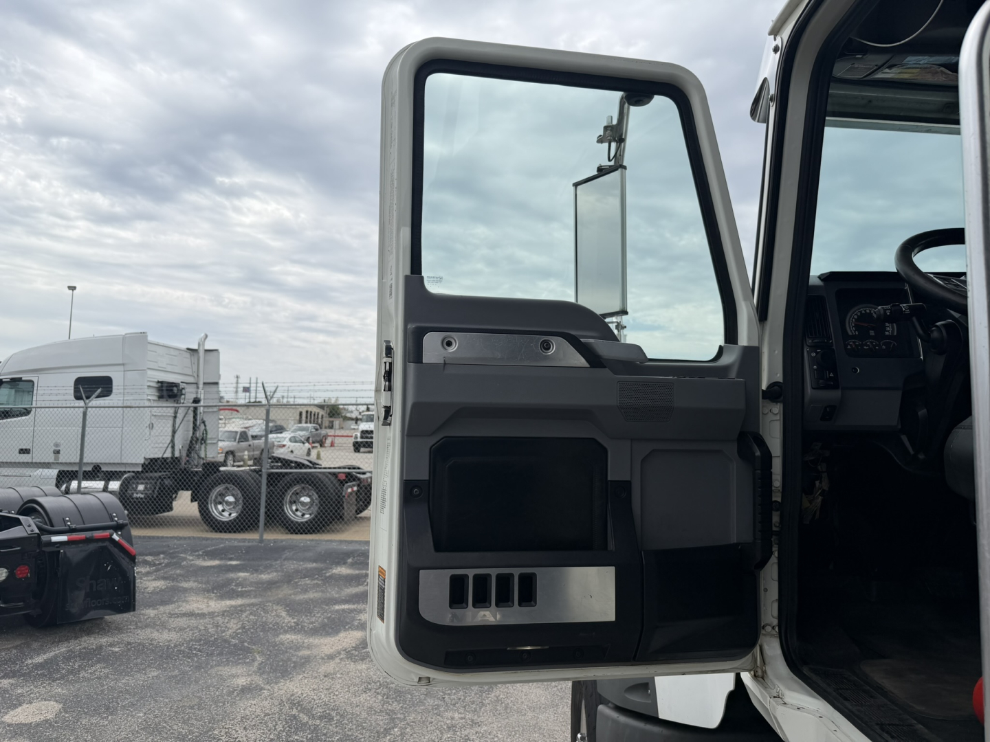Truck cab door interior panel view showing storage pocket and window controls in a Mack GR64F truck cabin.
