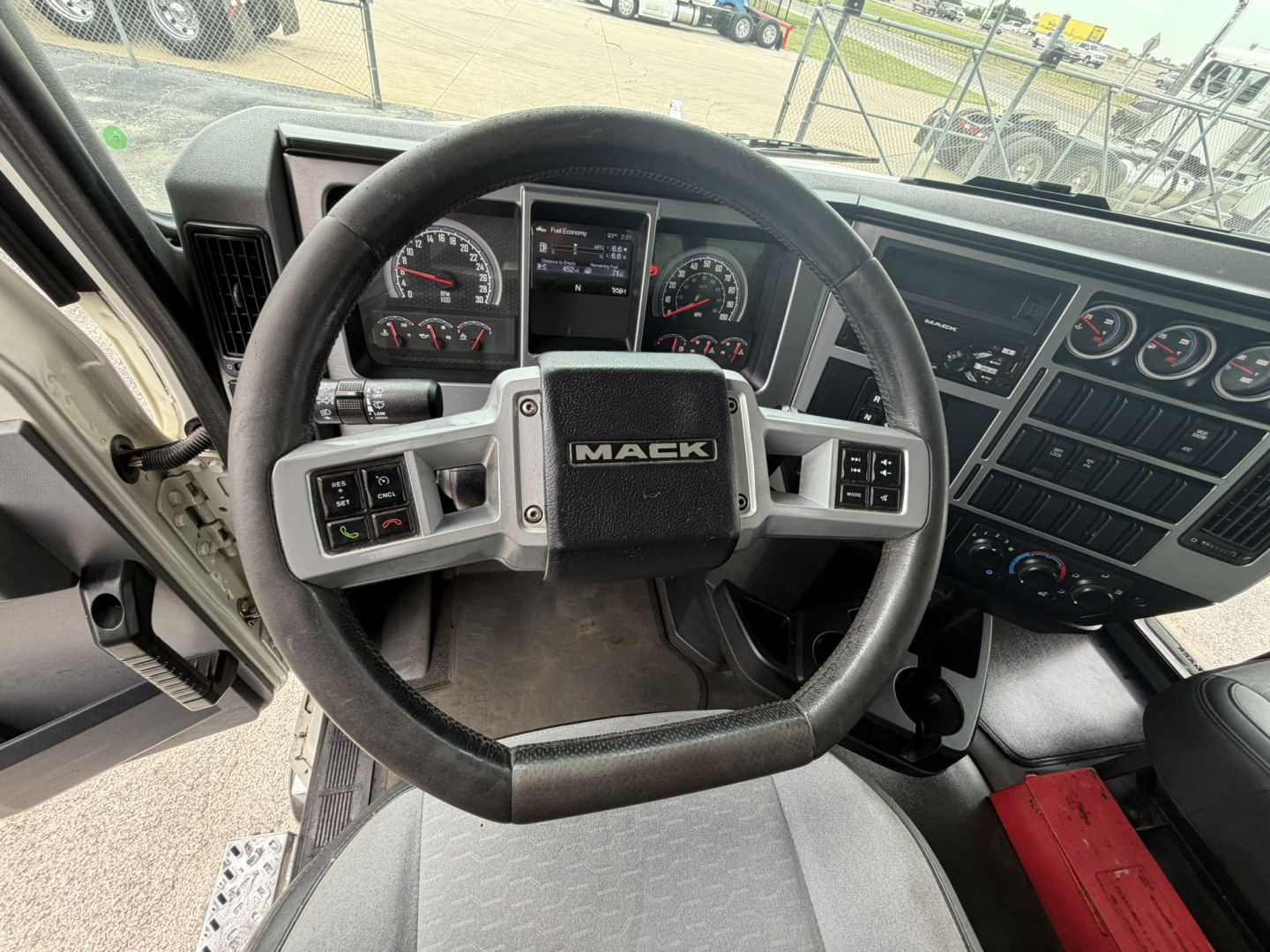 Mack GR64F truck dash and steering wheel interior showing Mack logo and gauges.