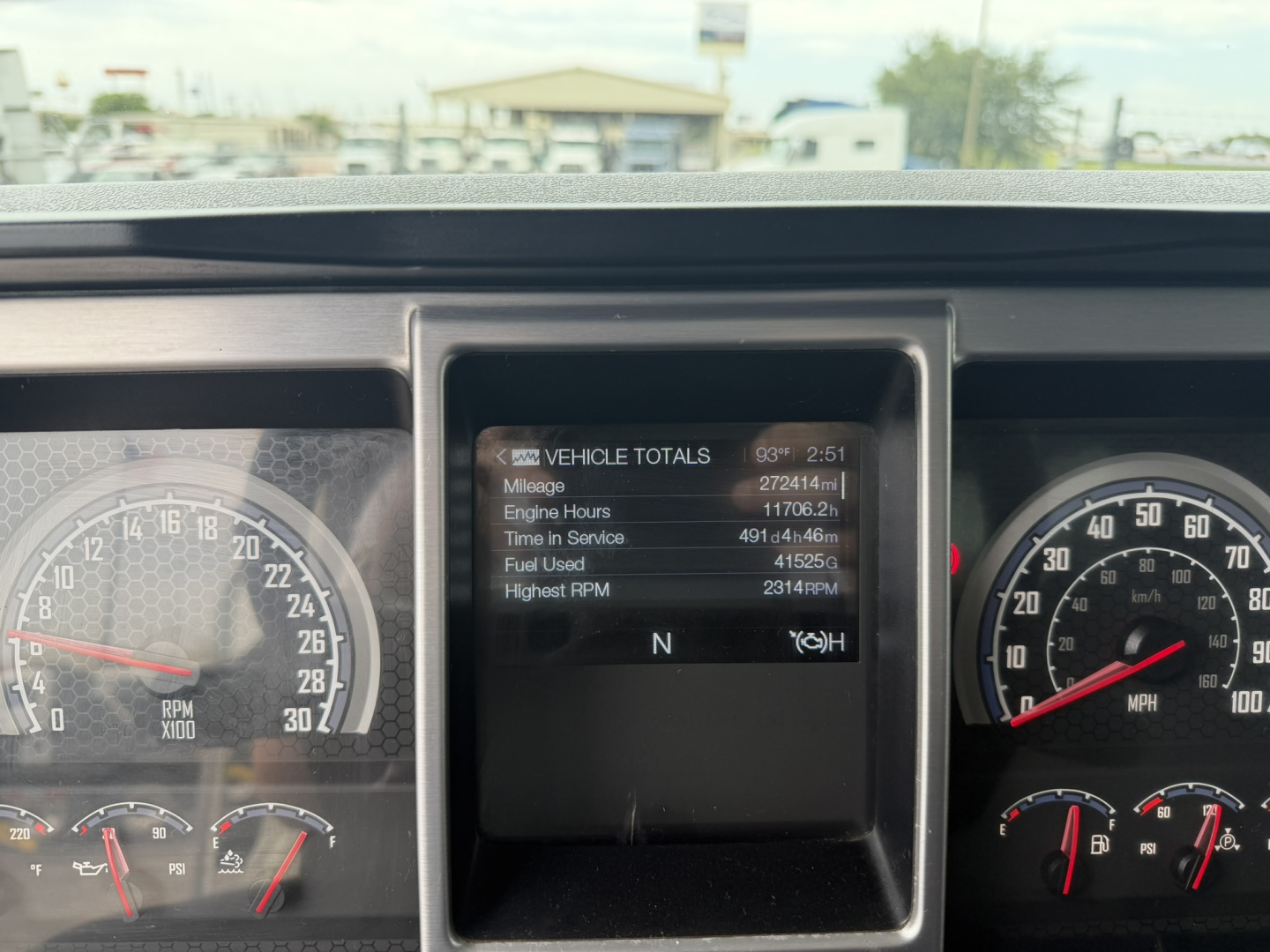 Dashboard view of a 2021 Mack GR64F dump truck showing the central display with vehicle totals and gauges on left and right.