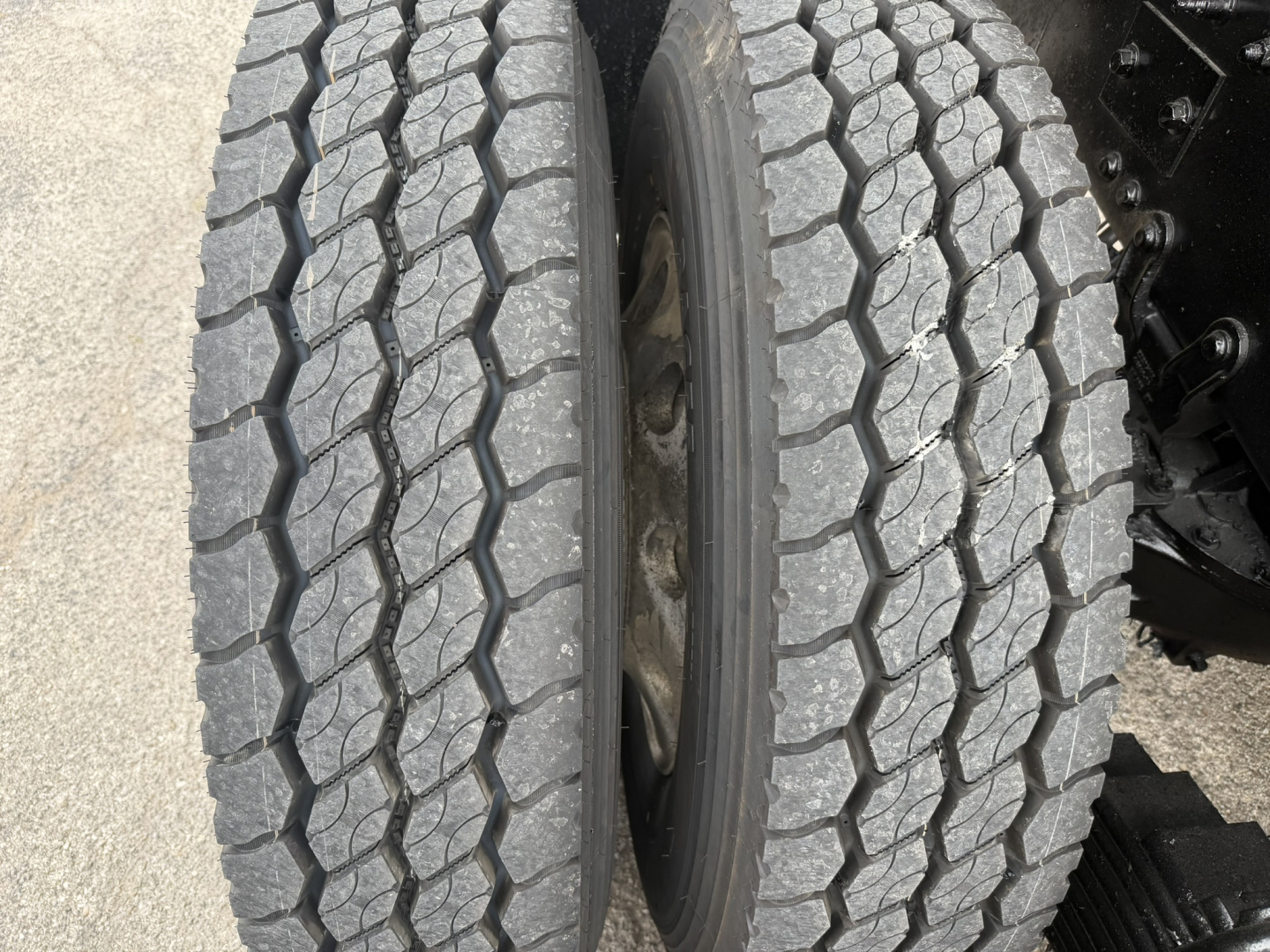 Wheel end showing two dual rear tires with tread pattern and inner hub area of a Mack GR64F truck.