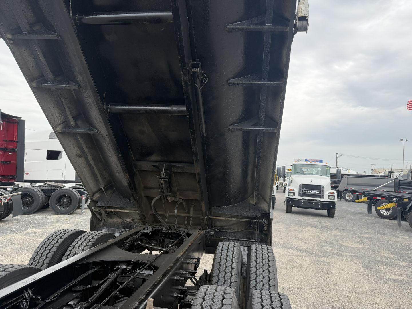 Dump truck bed raised showing chassis and tandem rear tires under the dump body.