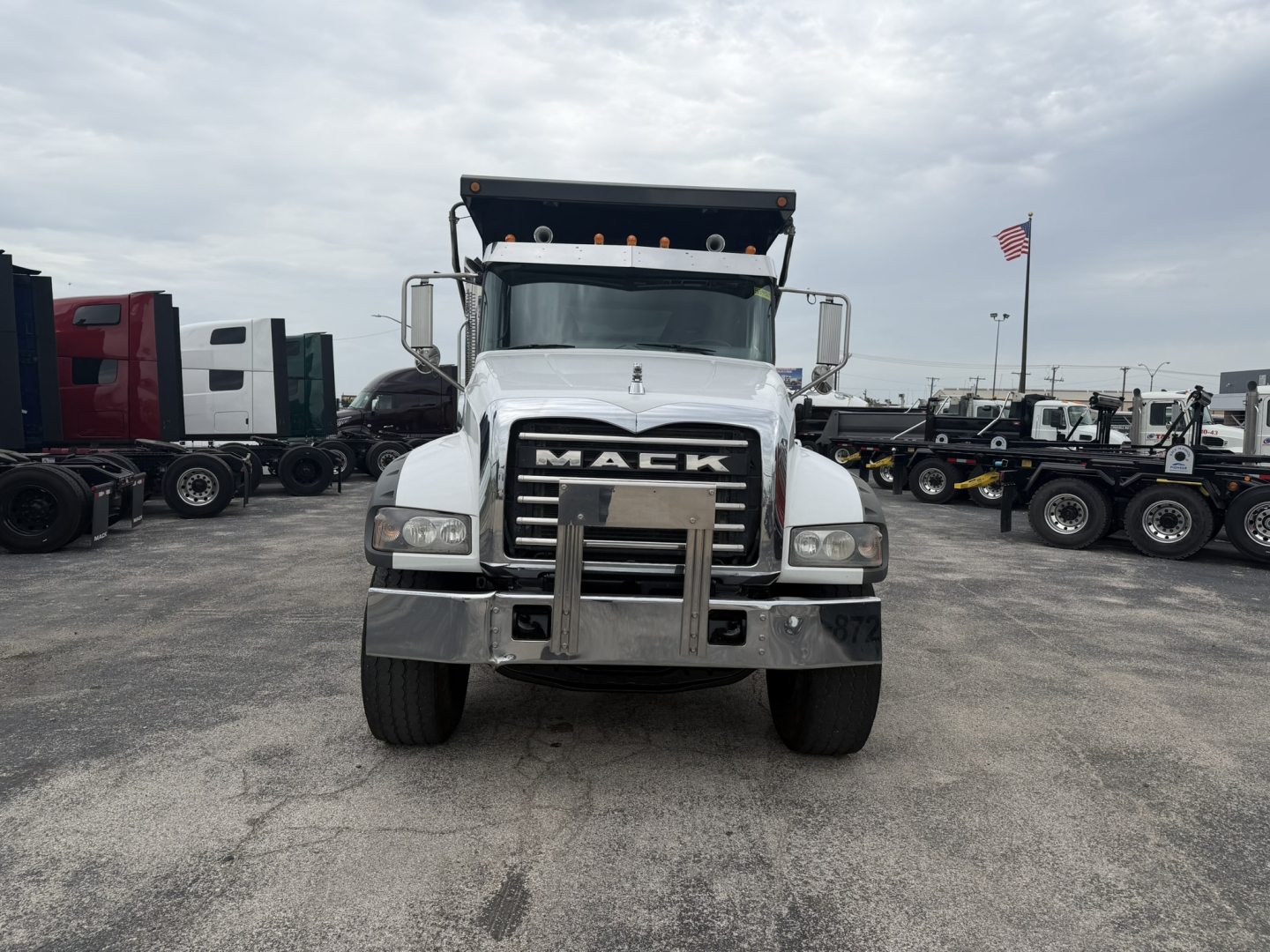 Mack GR64F dump truck front view showing chrome grille with MACK emblem and elevated dump bed behind cab.