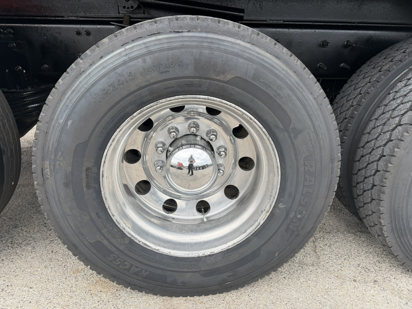 Rear wheel hub and tire of a Mack GR64F dump truck showing polished aluminum rim and black tire.