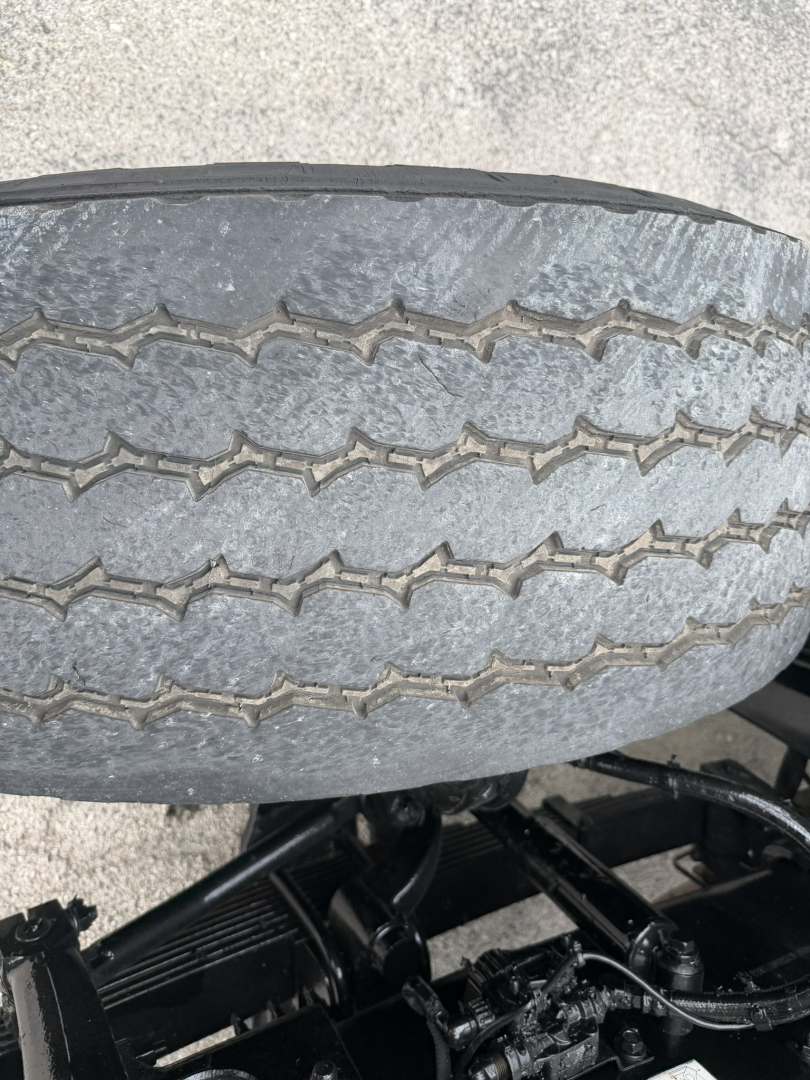 Tire tread close-up on a Mack GR64F dump truck chassis showing duals and undercarriage components.