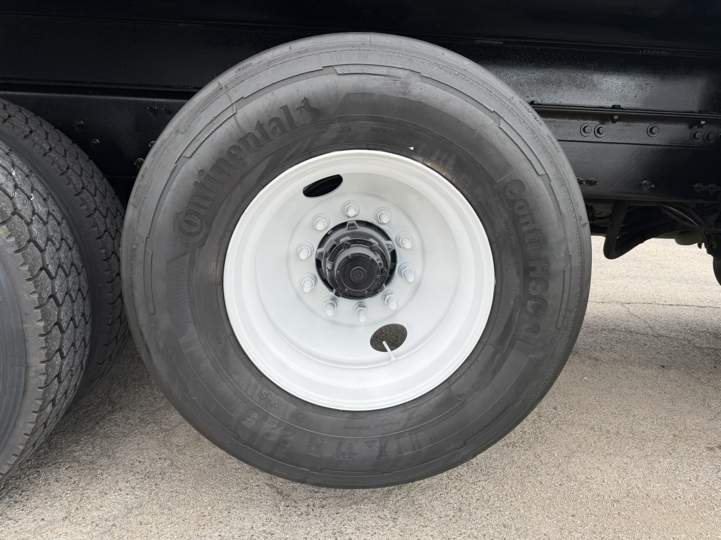 Dually truck wheel showing ContiContinental tire on white steel rim under truck chassis.