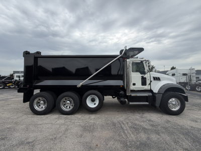 2021 Mack GR64F dump truck side view showing black dump body, white cab, wheels, and hydraulic dump mechanism.