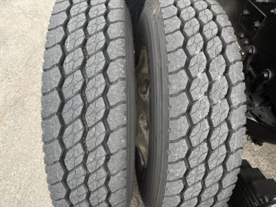Wheel end showing two dual rear tires with tread pattern and inner hub area of a Mack GR64F truck.