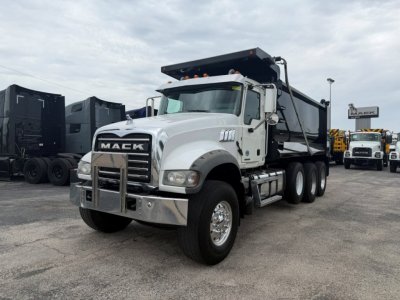 Mack GR64F dump truck in a dealership lot showing front-left view with chrome bumper and Maek grille.