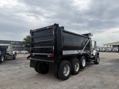 Dump truck rear and side view showing three-axle Mack GR64F dump bed with black bed and white cab, drivetrain and wheel setup visible.