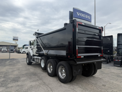 Mack GR64F dump truck rear view showing black dump bed and Volvo dealership sign