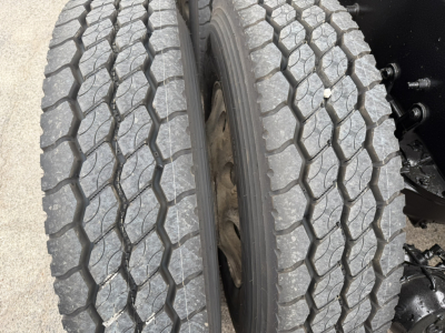 Truck wheel pair showing heavy tread with hexagonal pattern on front dual tires for a 2021 Mack GR64F dump truck.