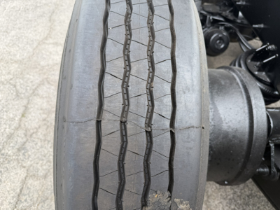 Front wheel and dual rear axle of a Mack GR64F dump truck showing treaded tire profile and wheel hub.