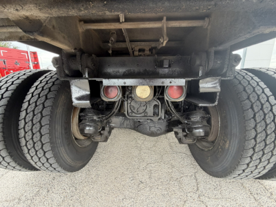 Mack GR64F rear undercarriage showing dual rear axles, suspension components, and underside frame with three circular access ports and differential housing.