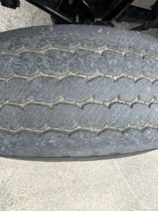 Truck tire close-up showing tread pattern on a Mack GR64F dump truck wheel.