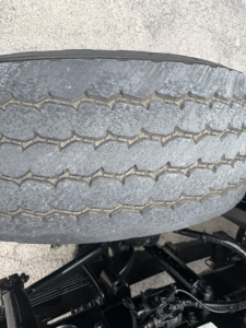 Tire tread close-up on a Mack GR64F dump truck chassis showing duals and undercarriage components.