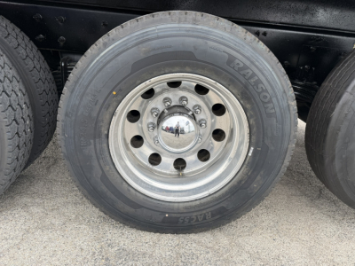 Wheel and tire on Mack GR64F truck showing coil spring hub and RALISON?? brand On tire sidewall with text 'TALISON' or 'RAISON'? The visible text includes 'RAISON' and 'EAGLE' maybe. chrome center cap reflection. Rim with multiple lug nuts.