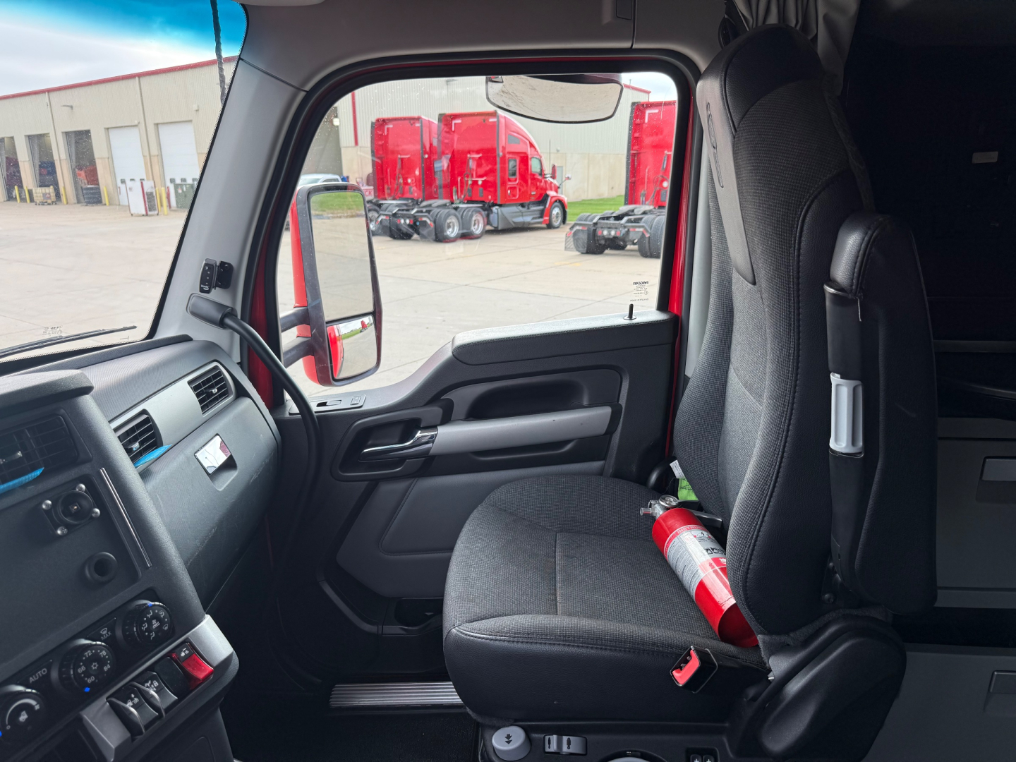 Kenworth T680 cab interior showing front passenger seat and dashboard with emergency fire extinguisher in view.