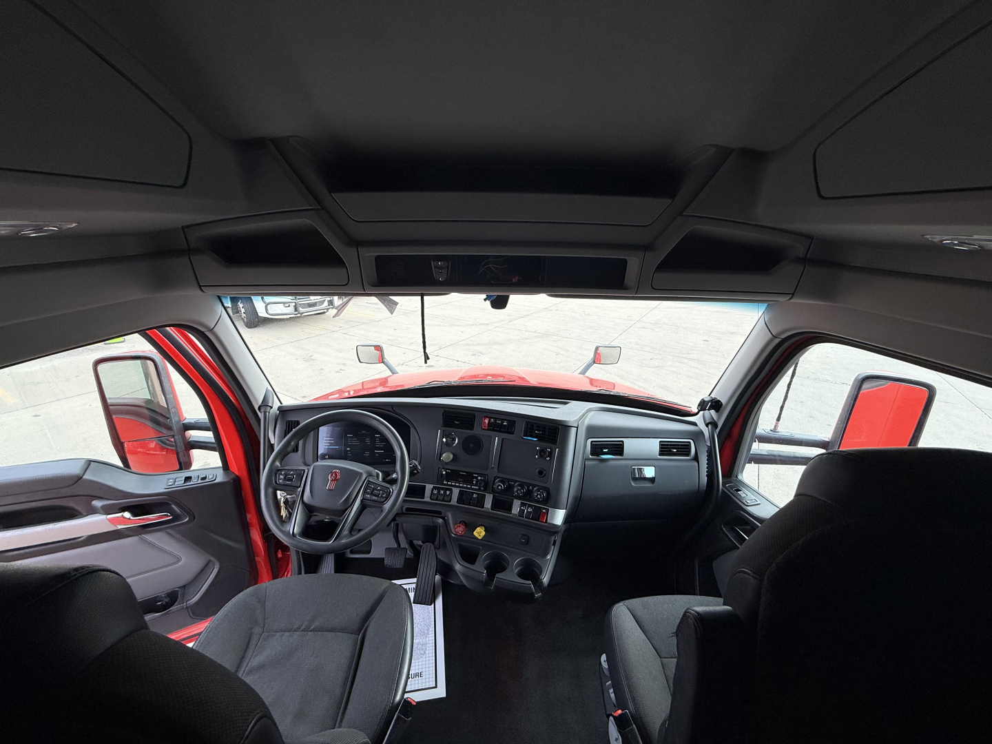 Kenworth T680 truck cockpit interior with steering wheel, dashboard, and seats viewable from front cabin.