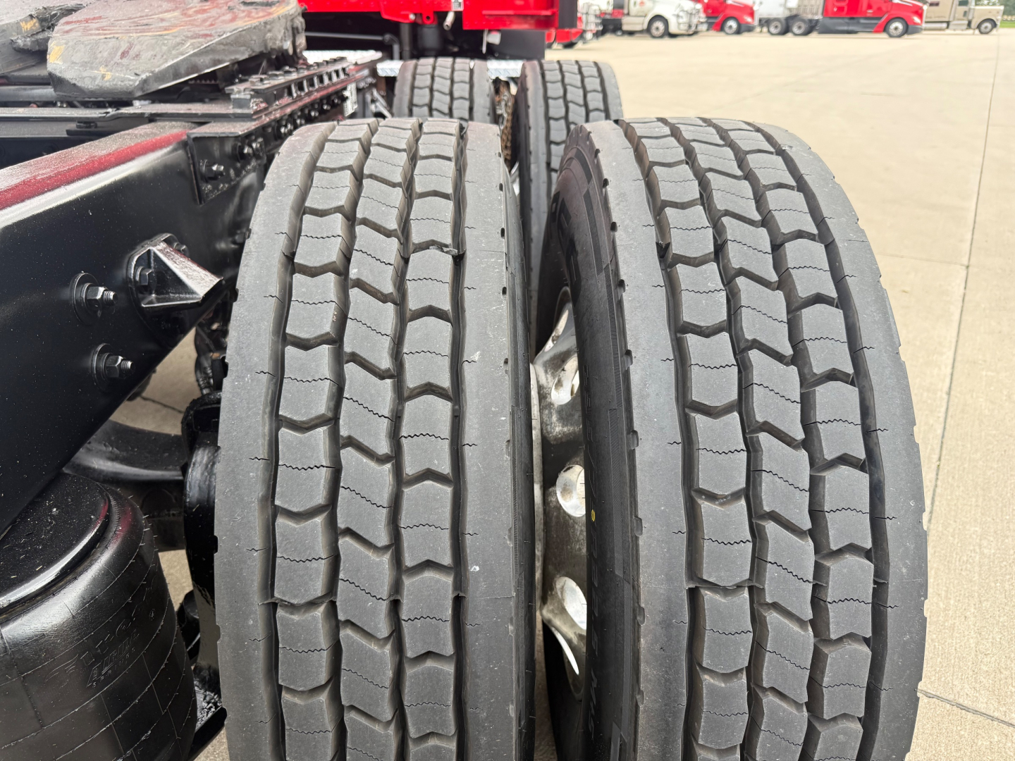 Kenworth T680 wheel area showing dual rear tires and part of chassis in a truck yard.