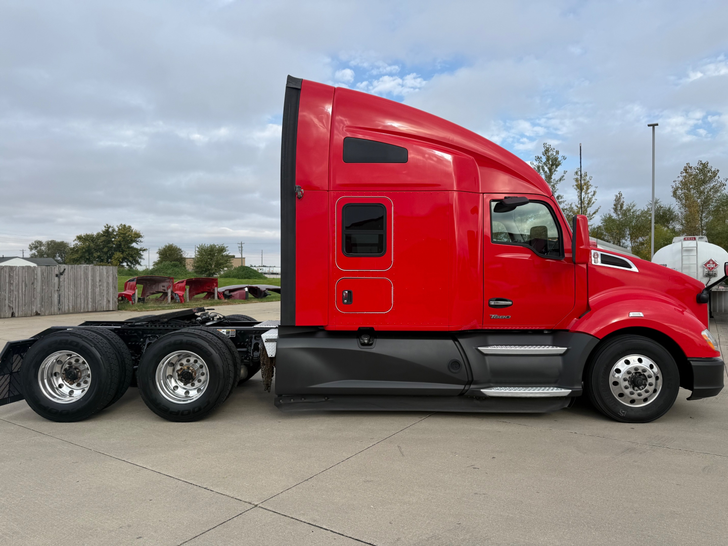 Kenworth T680 side view showing red sleeper cab and dual rear axles.