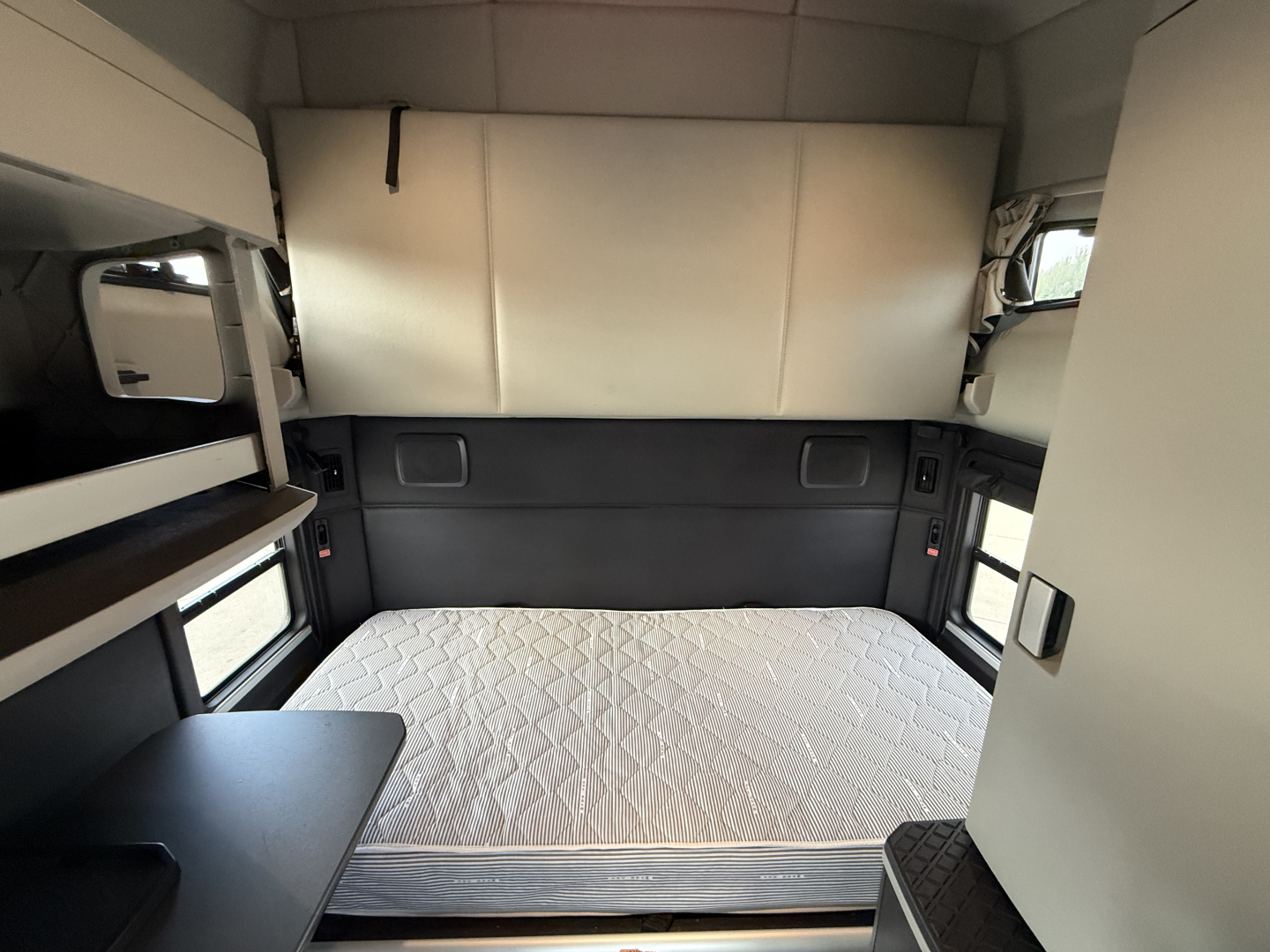 Kenworth T680 truck sleeper cabin interior with bed, window shades, and storage shelves visible.