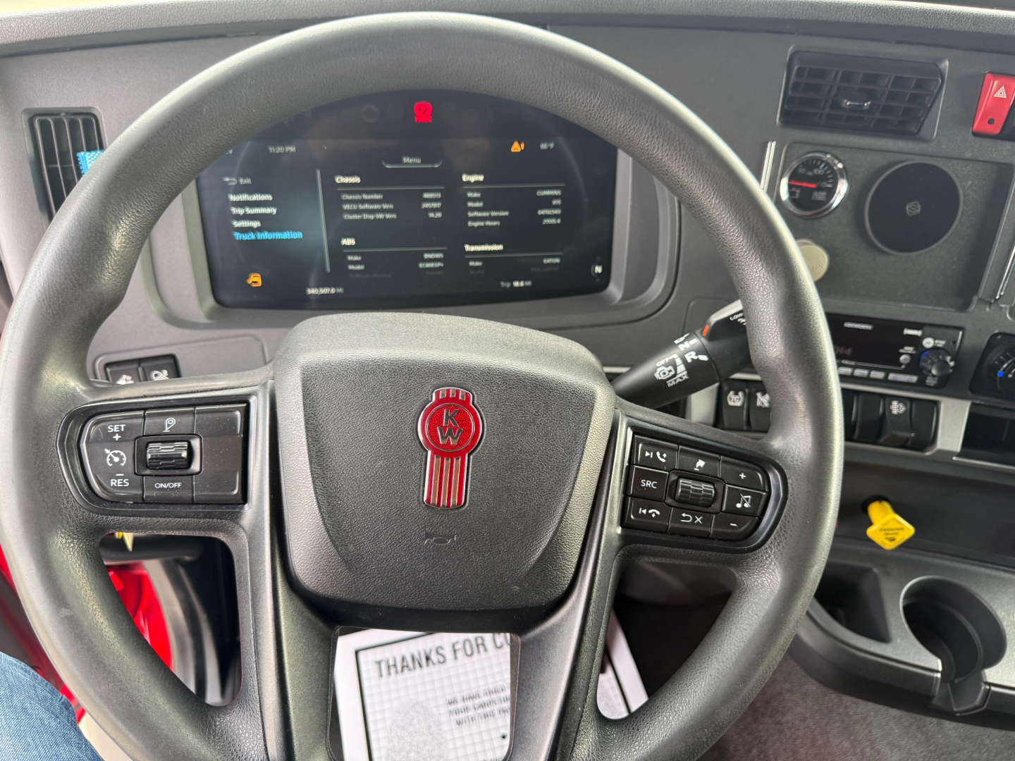 Kenworth T680 steering wheel and dashboard showing instrument cluster and control buttons.