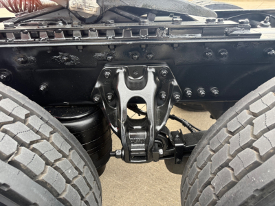 Kenworth T680 chassis view showing suspension and drivetrain components between dual rear wheels.