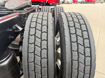 Kenworth T680 wheel area showing dual rear tires and part of chassis in a truck yard.