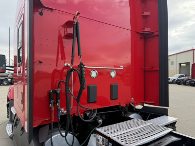 Kenworth T680 rear cab area showing ladder step and hookups with hoses and hardware in view.