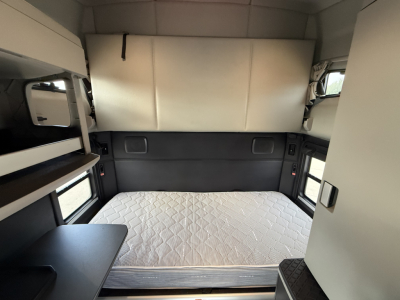 Kenworth T680 truck sleeper cabin interior with bed, window shades, and storage shelves visible.