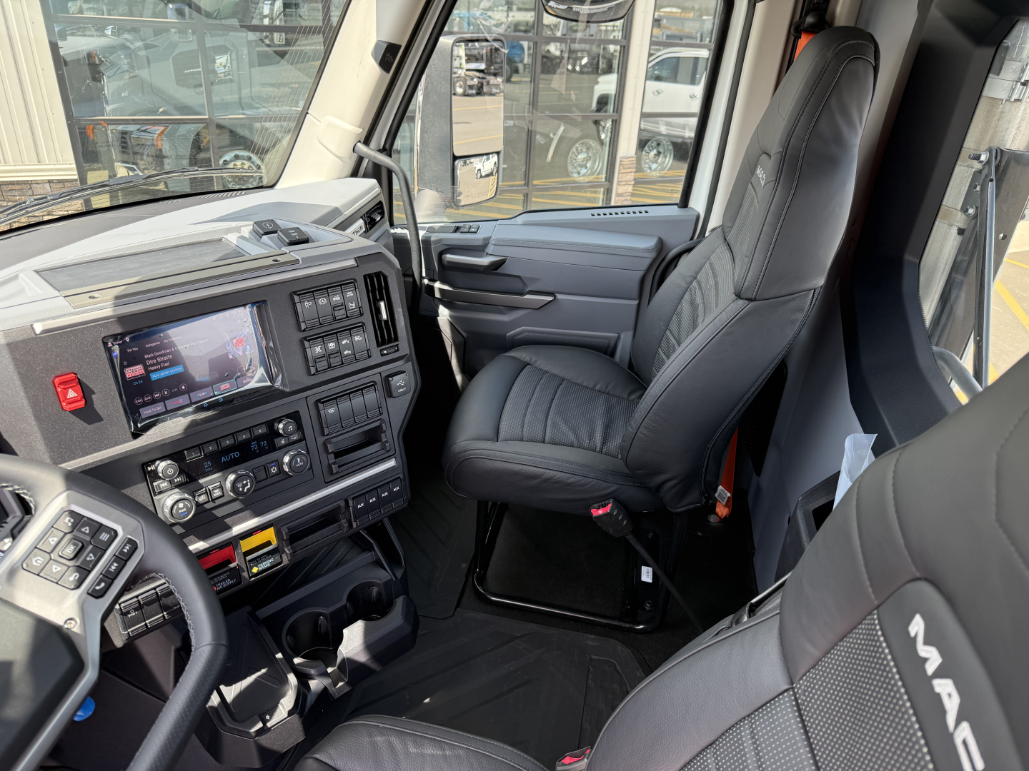Interior view of a new 2027 Mack AN64T daycab truck cab with leather-like seats and dashboard controls.