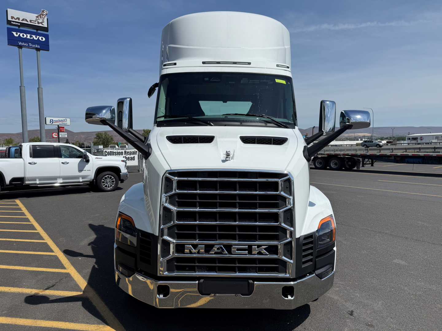 Front view of a white 2027 Mack AN64T conventional day cab truck showing large chrome grille with MACK letters and side mirrors.