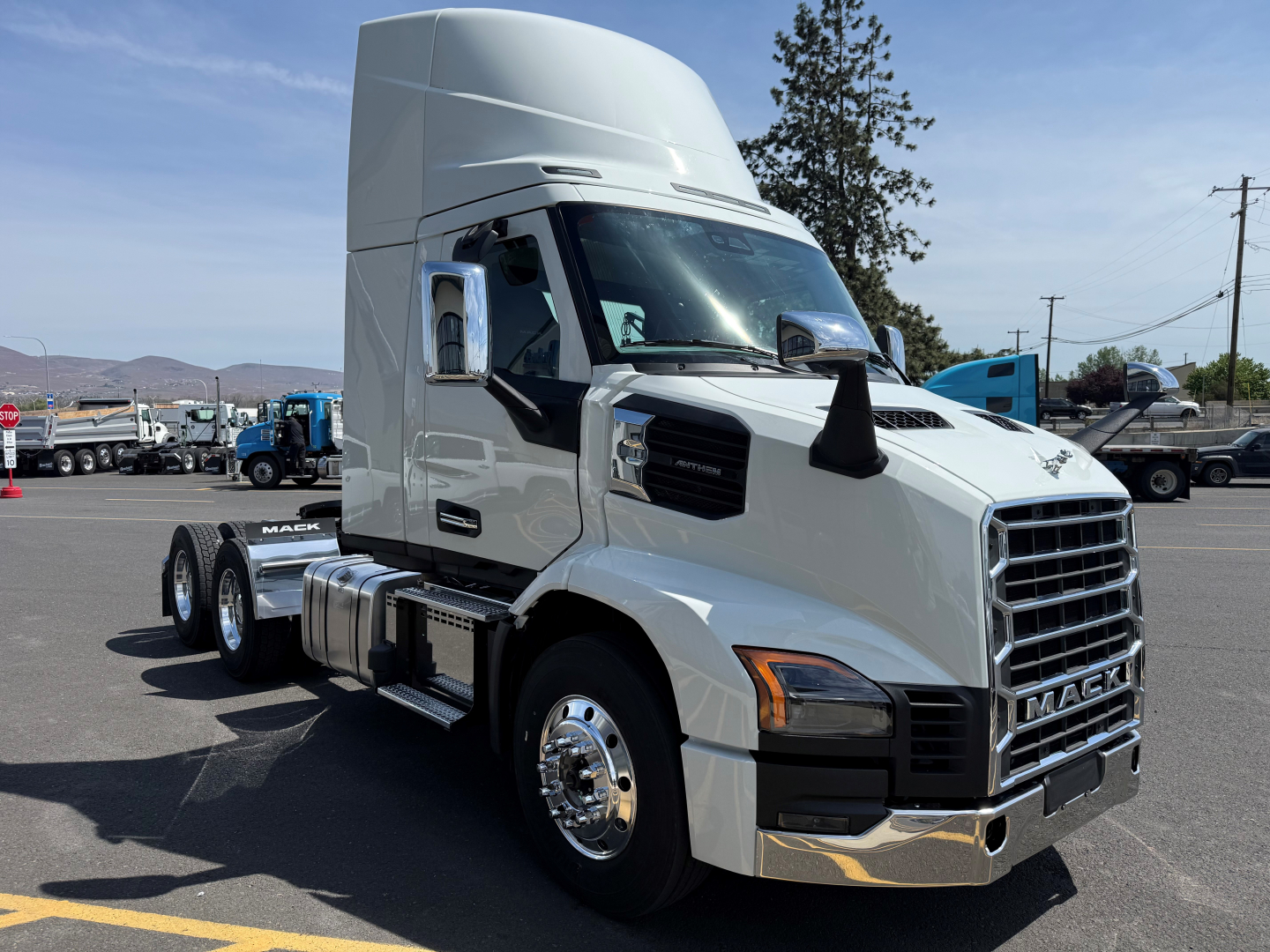 Conventional daycab truck front-left view showing Mack AN64T cab with chrome grille and dual rear axles.