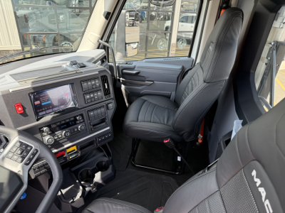 Interior view of a new 2027 Mack AN64T daycab truck cab with leather-like seats and dashboard controls.