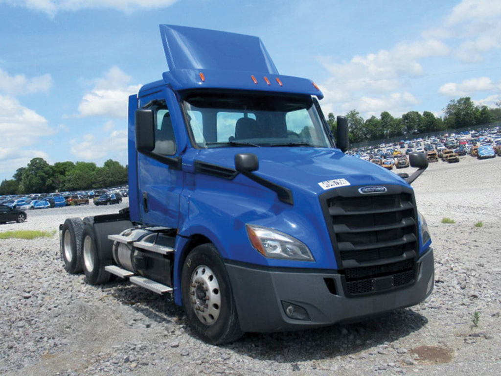 Blue 2022 Freightliner Cascadia125/126 conventional daycab truck with raised hood and long sleeper in a gravel lot.