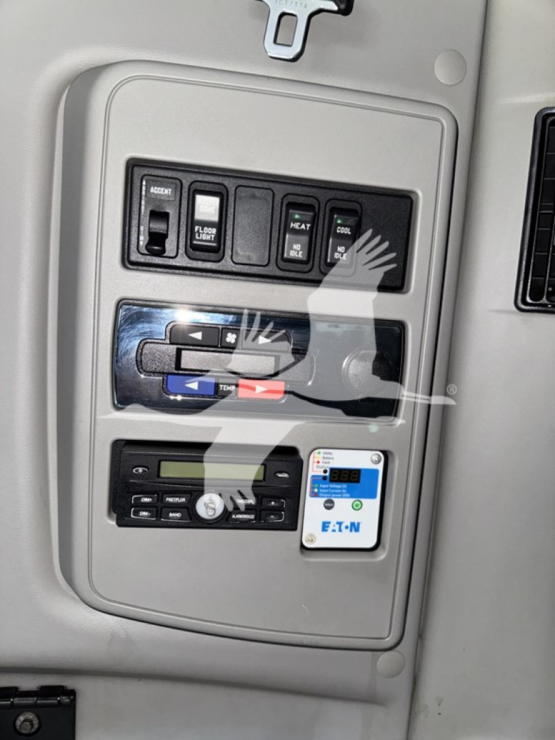 Panel with switches and gauges on a truck interior: labels include ACC, DEF LO, HEAT, FUEL, etc. Also a small blue-white EAT-N label and a digital display near bottom.