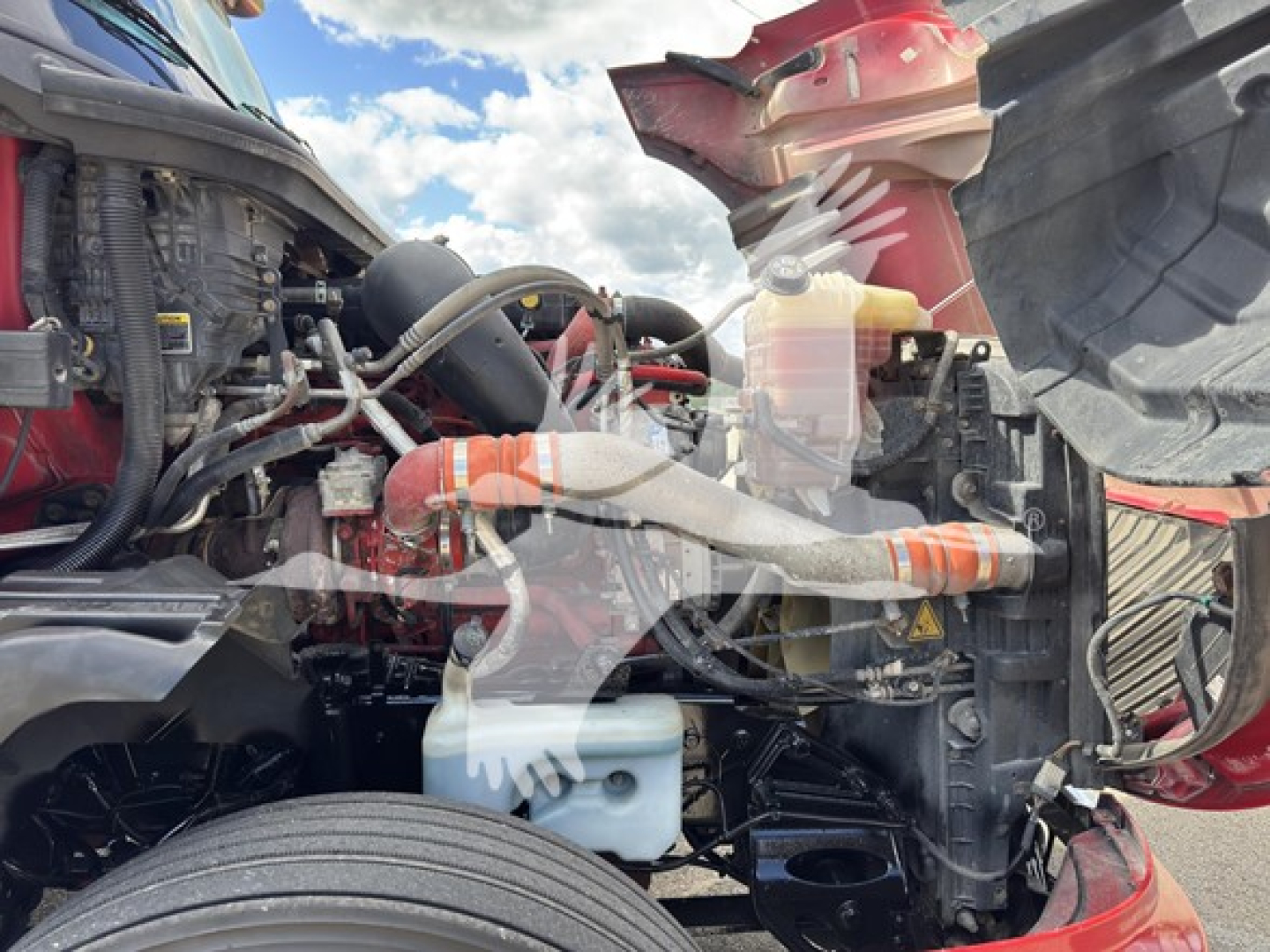 Truck engine bay of a 2019 International LT showing coolant reservoir, hoses, and various engine components in view.