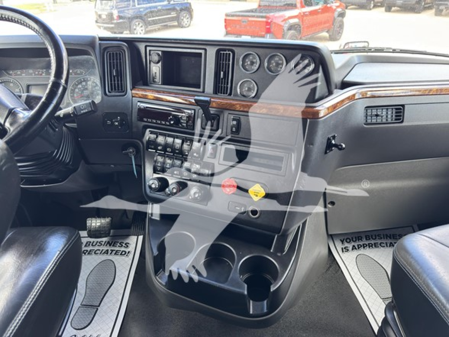 Dashboard and center console of a 2019 International LT truck showing steering column, gauges, switches, and cup holders.