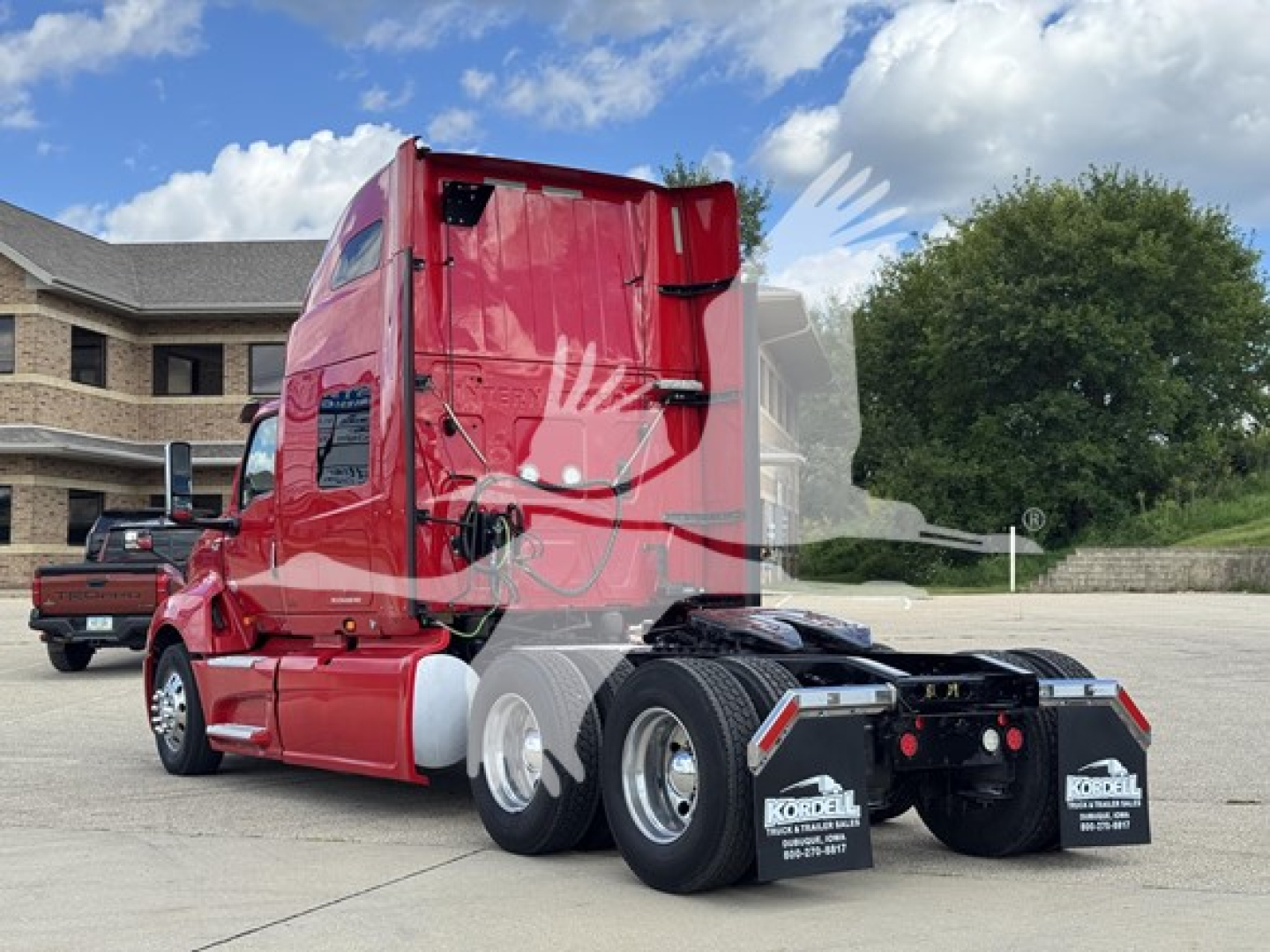 Truck tractor in red cab view from rear-left showing 6x4 configuration and sleeper, with dual rear axles and mud flaps.