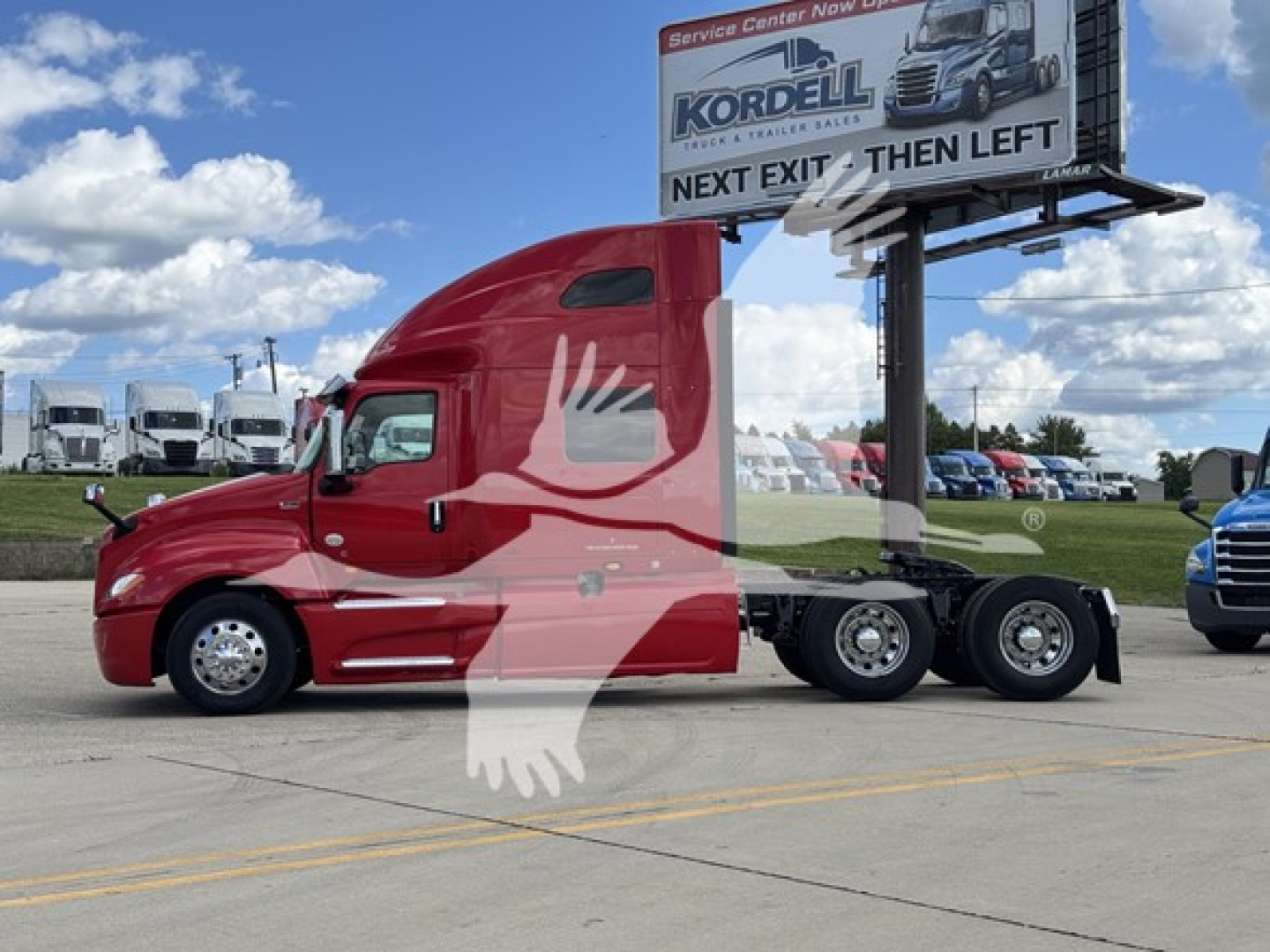 Red semi tractor cab in a parking lot with a billboard on a trailer, International LT model, side view.