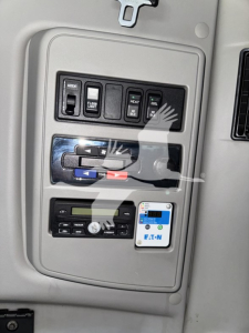 Panel with switches and gauges on a truck interior: labels include ACC, DEF LO, HEAT, FUEL, etc. Also a small blue-white EAT-N label and a digital display near bottom.