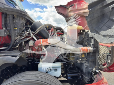 Truck engine bay of a 2019 International LT showing coolant reservoir, hoses, and various engine components in view.