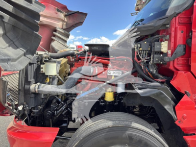 Truck engine bay of a red 2019 International LT with exposed engine components, intercooler piping, and air intake showing 6x4 badge, hoses, and a large front wheel visible