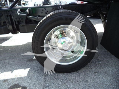 Wheel and tire assembly on truck frame showing shiny steel rim and hub with bolts.