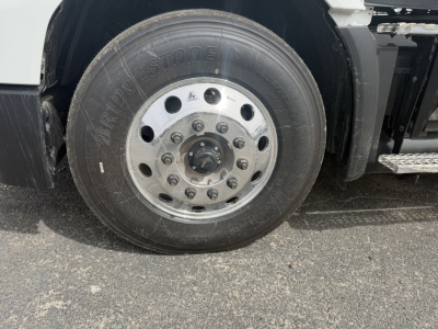 Mack AN64T truck front wheel showing Bridgestone tire and polished aluminum wheel with lug nuts and hub.