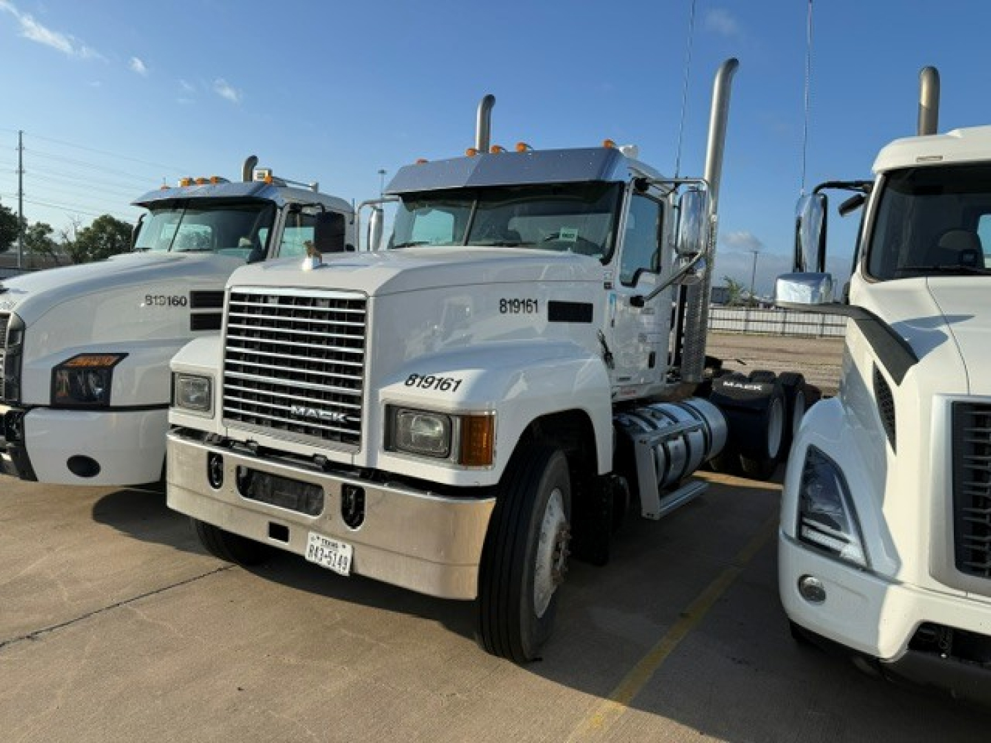 Mack PI64T conventional daycab truck in a lineup showing front grille and bumper with chassis and exhaust stacks.