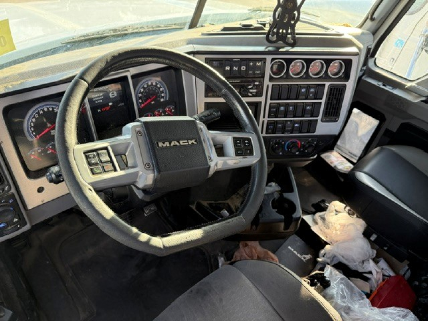 Cab interior of a 2019 Mack PI64T daycab showing steering wheel with Mack emblem and instrument cluster, center console controls, and dashboard gauges.