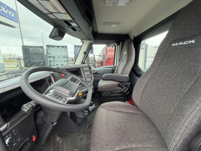 Cab interior of a 2027 Mack AN64T daycab showing steering wheel, driver seat with Mack logo, dashboard, and central control cluster.