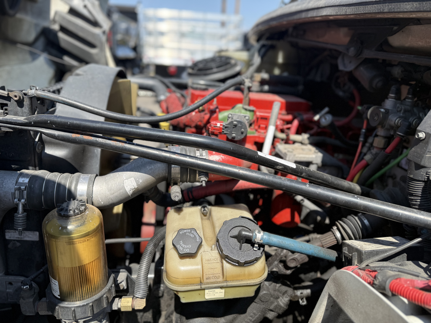 Freightliner M2106 engine bay showing coolant reservoir and various hoses.
