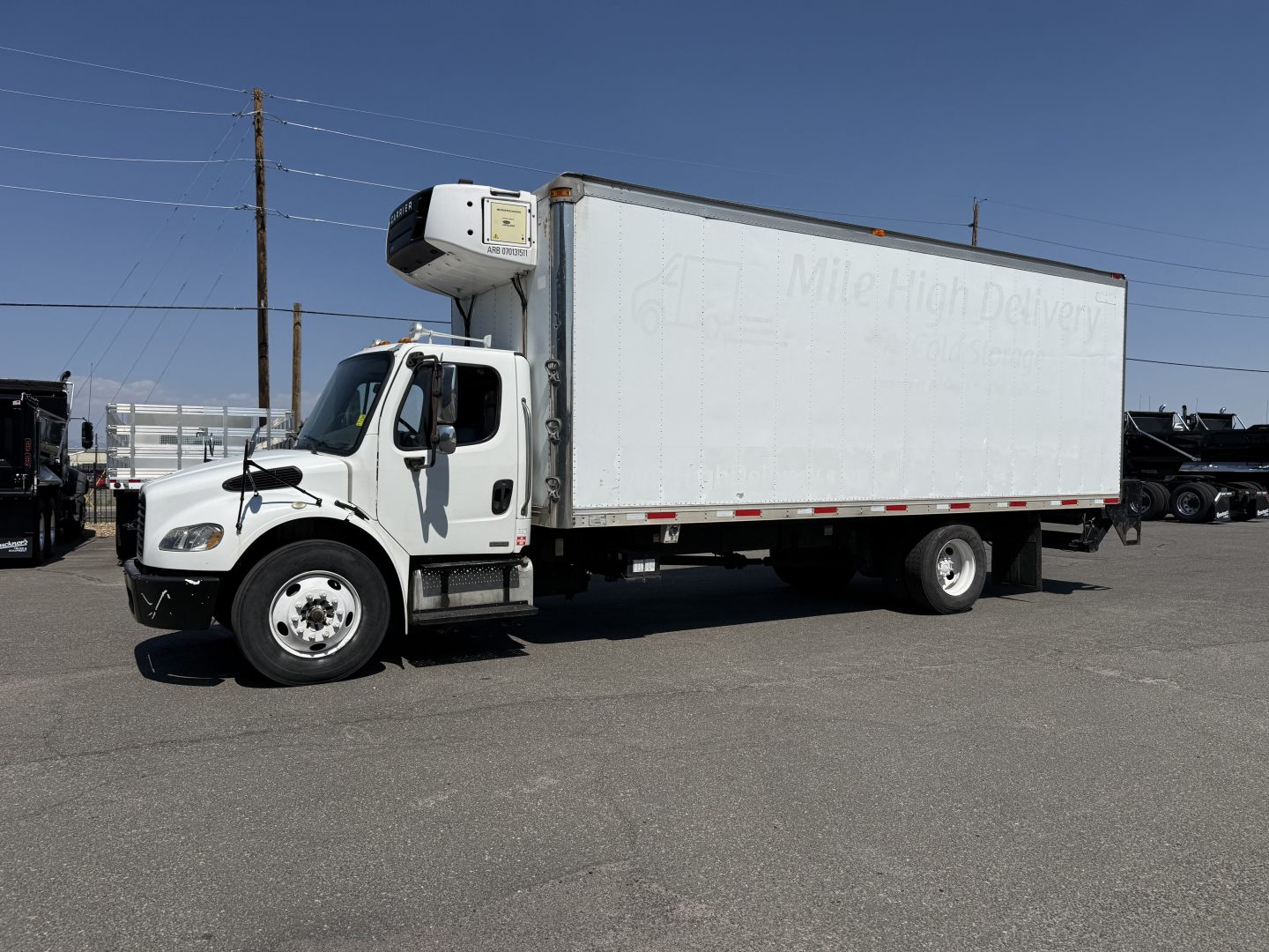 Freightliner M2106 refrigerated truck with white box and side refrigeration unit, side view showing cab and cargo area.